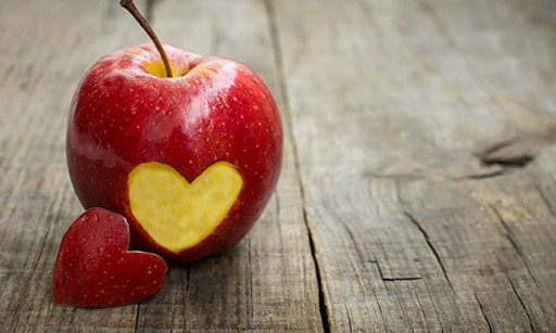 A red apple with a heart-shaped bite taken out of it.