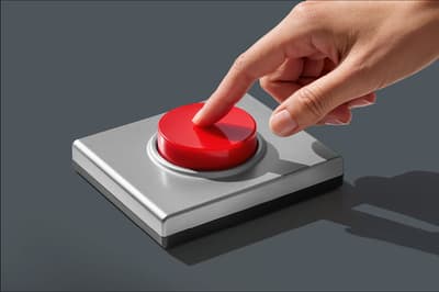 A hand pressing a large red button on a grey control panel, illustrating the moment insight turns into action.