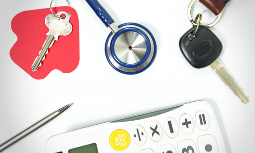 A calculator, a house key, a car key, and a pen, all surrounding the end of a stethoscope.