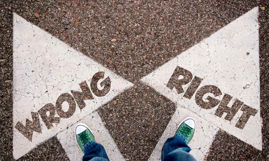 Someone standing over two arrows painted on the ground, one pointing left with the word ‘Wrong’ and the other pointing right with the word ‘Right’.