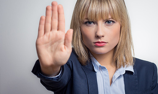 A woman in a business suit holding her hand up to the camera.