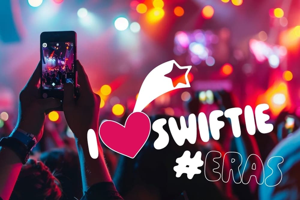 A concert crowd watching Taylor Swift live on stage taking pics on their mobiles