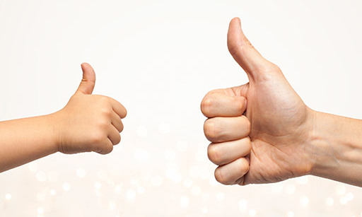 A child’s thumbs-up and an adult’s thumbs-up.